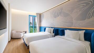 Habitación de hotel con dos camas, un ventanal grande, vista a palmeras y diseño moderno.
