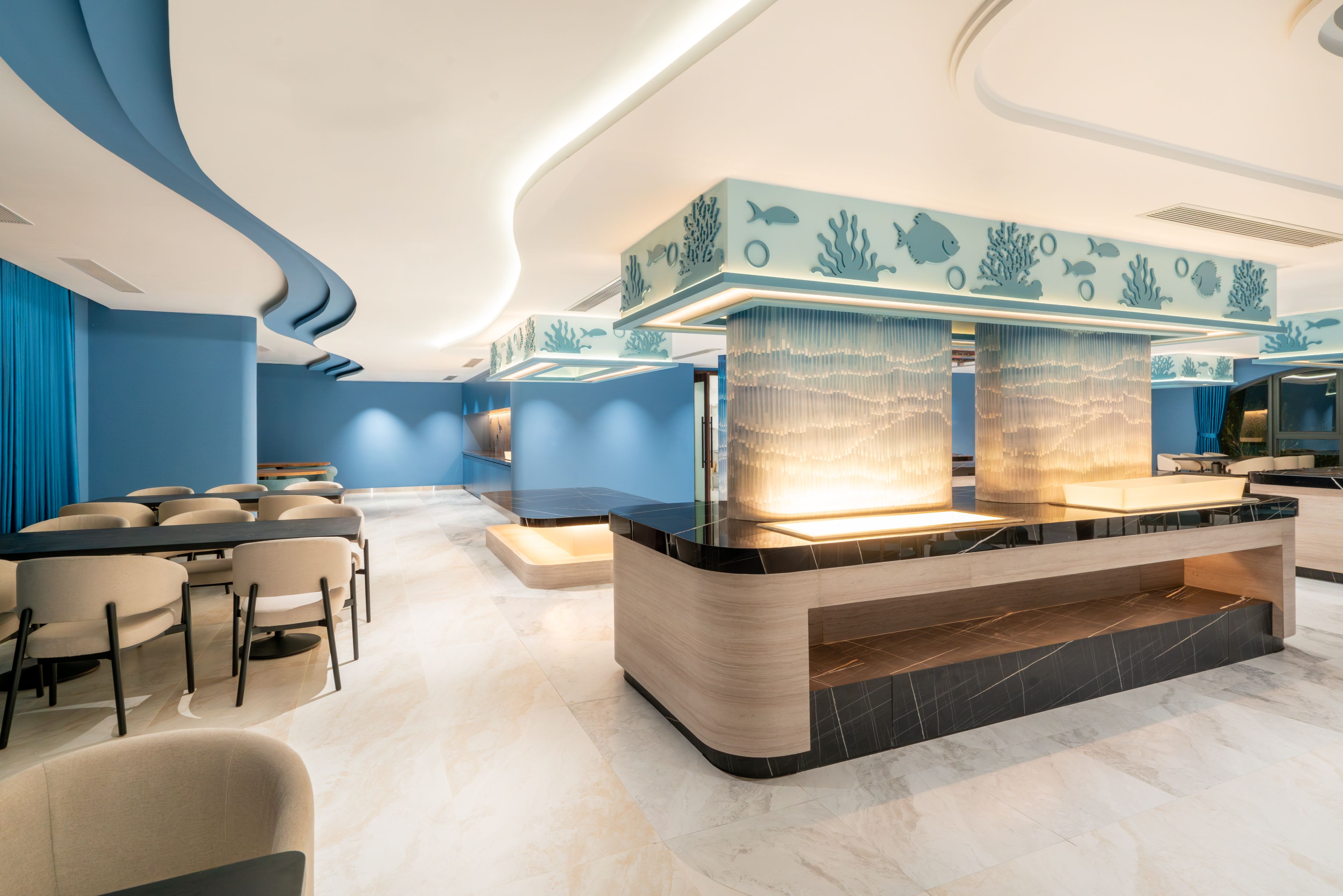 A modern bar area with a curved counter, seating, and a ceiling with blue wave patterns.