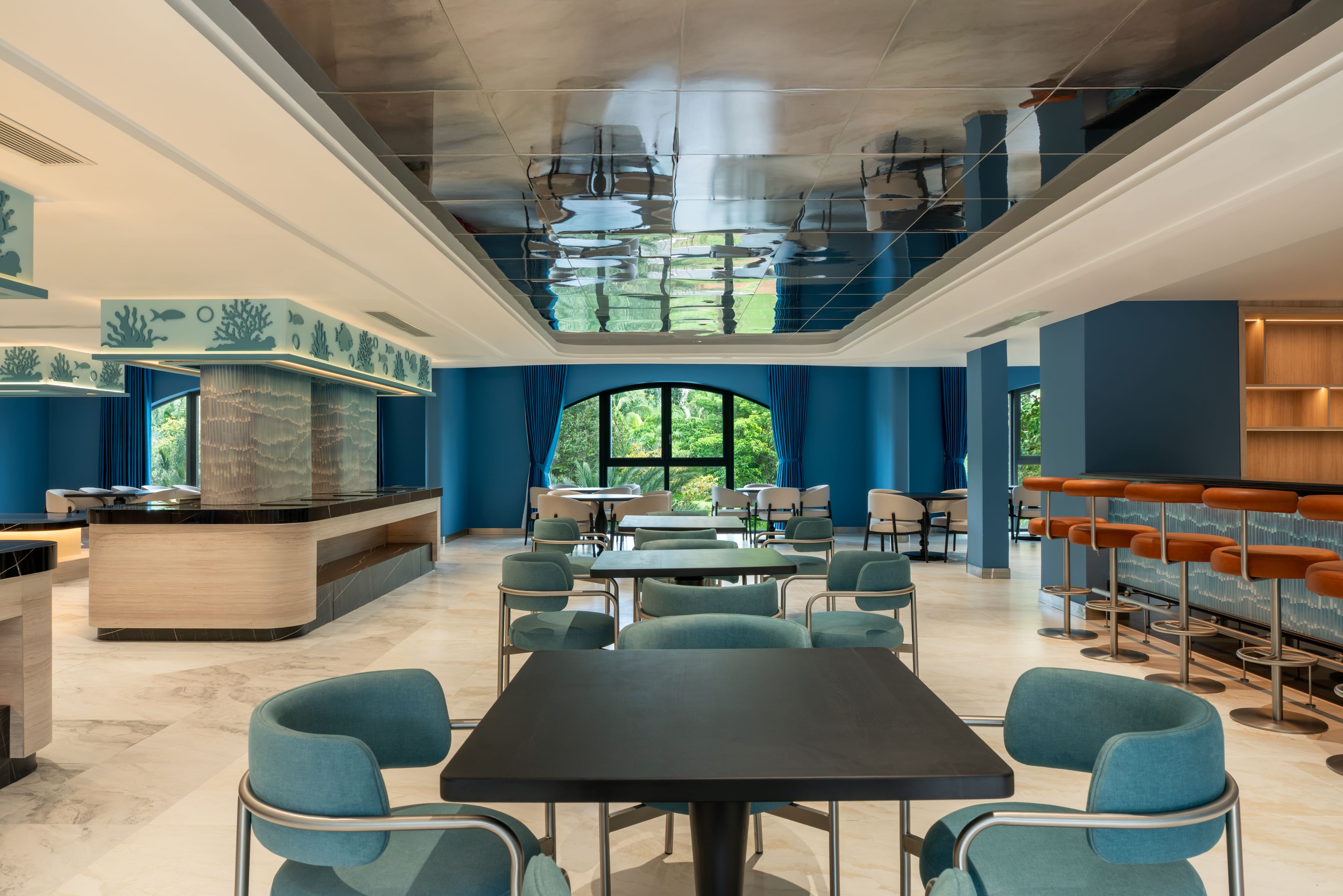 Un restaurant moderne doté d'une salle à manger centrale, d'un bar avec des tabourets et offrant une vue sur la verdure grâce à de grandes fenêtres.