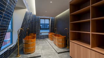 Un baño moderno con azulejos azul oscuro, tinas de madera y un amplio estante de madera.