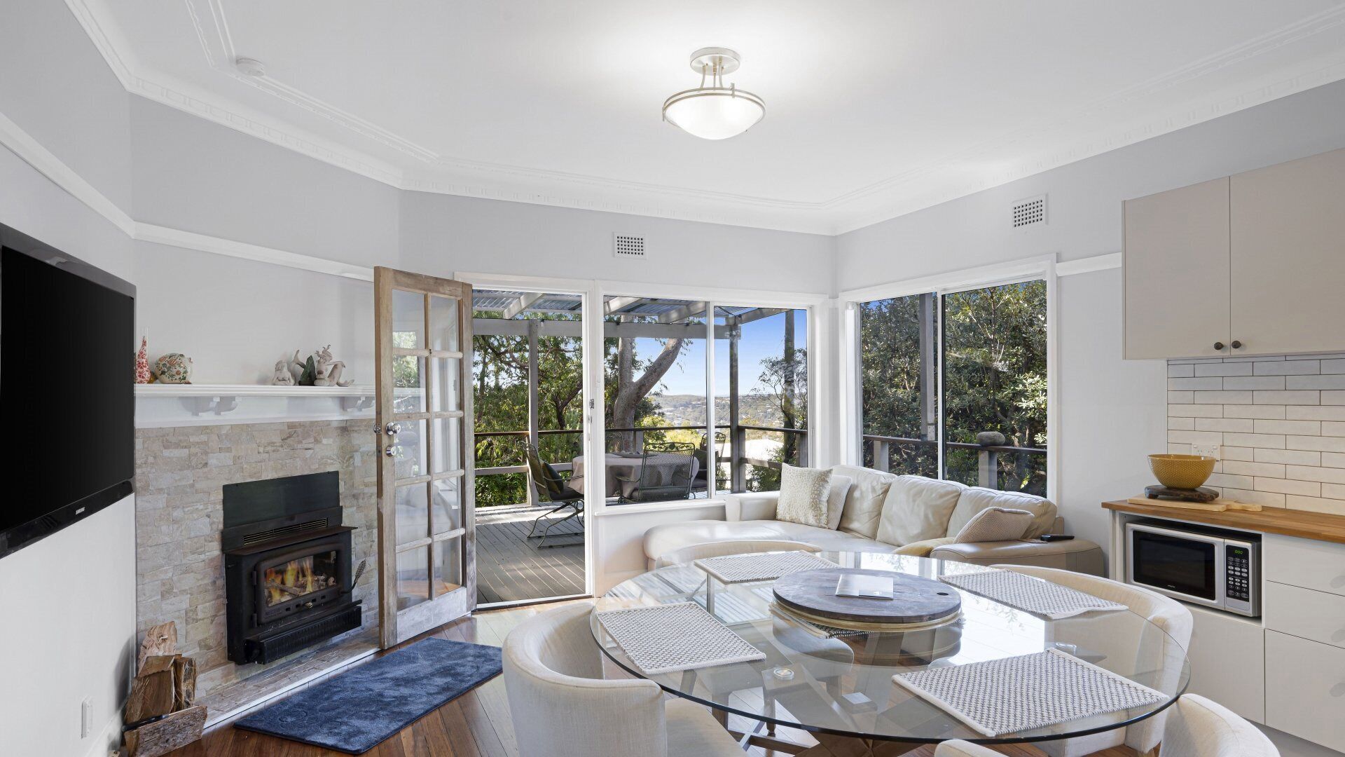 A modern living room with a fireplace, a glass dining table, and a sofa.