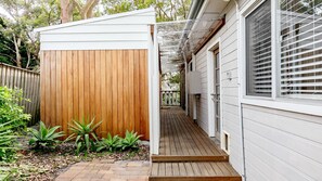 A wooden shed with a wooden deck leading to a house with white siding and a window with blinds. - Cottage plus grand/parents retreat (MACMASTERS BEACH)
