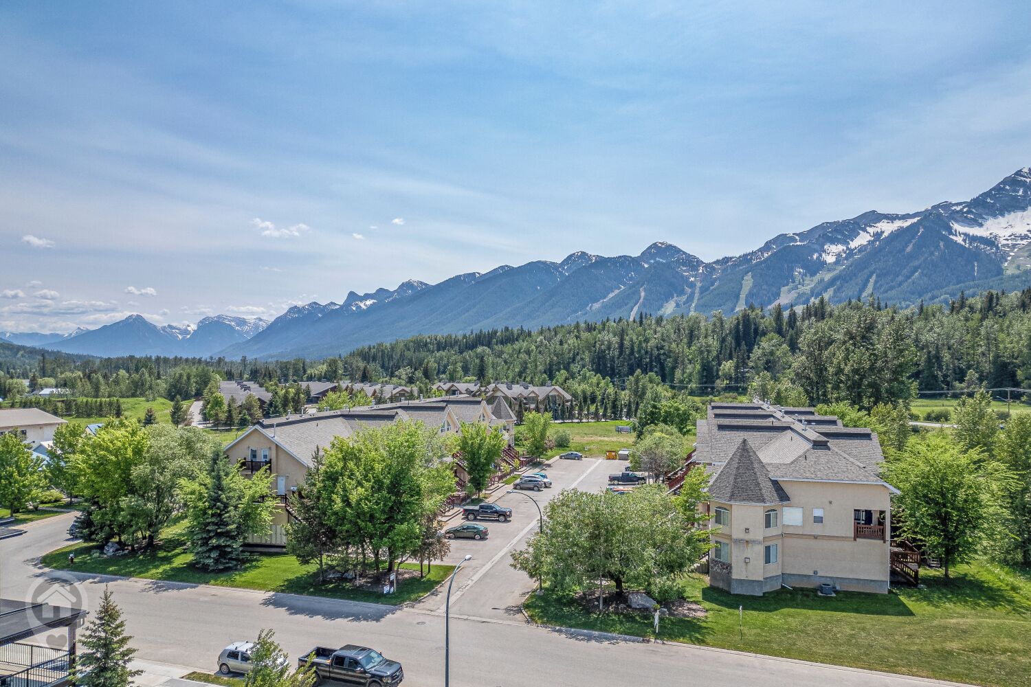 A residential area with houses, a parking lot, and a mountain range in the background.