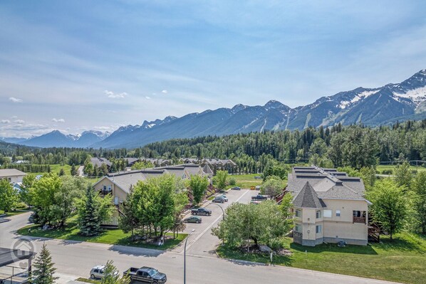 A residential area with houses, a parking lot, and a mountain range in the background.