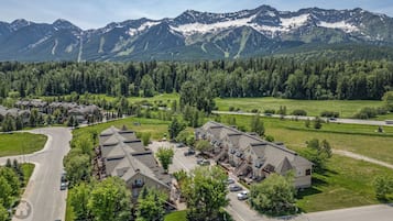A residential area with a row of houses, a curved road, and a mountain range in the background.