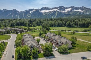 A residential area with a row of houses, a curved road, and a mountain range in the background.