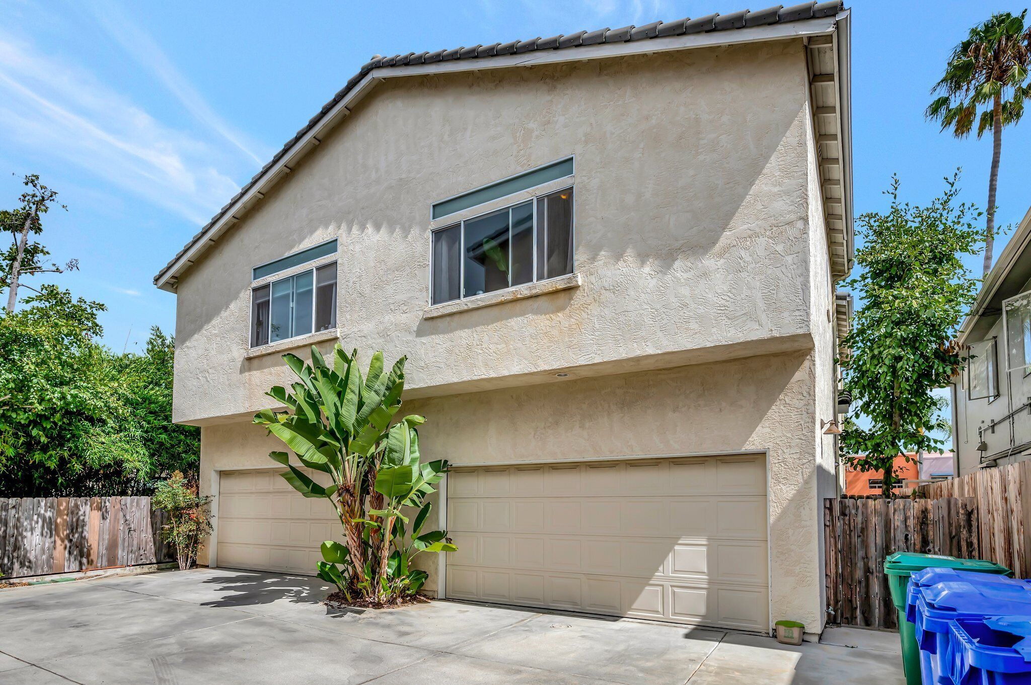 A two-story house with a garage, a small tree, and a wooden fence.