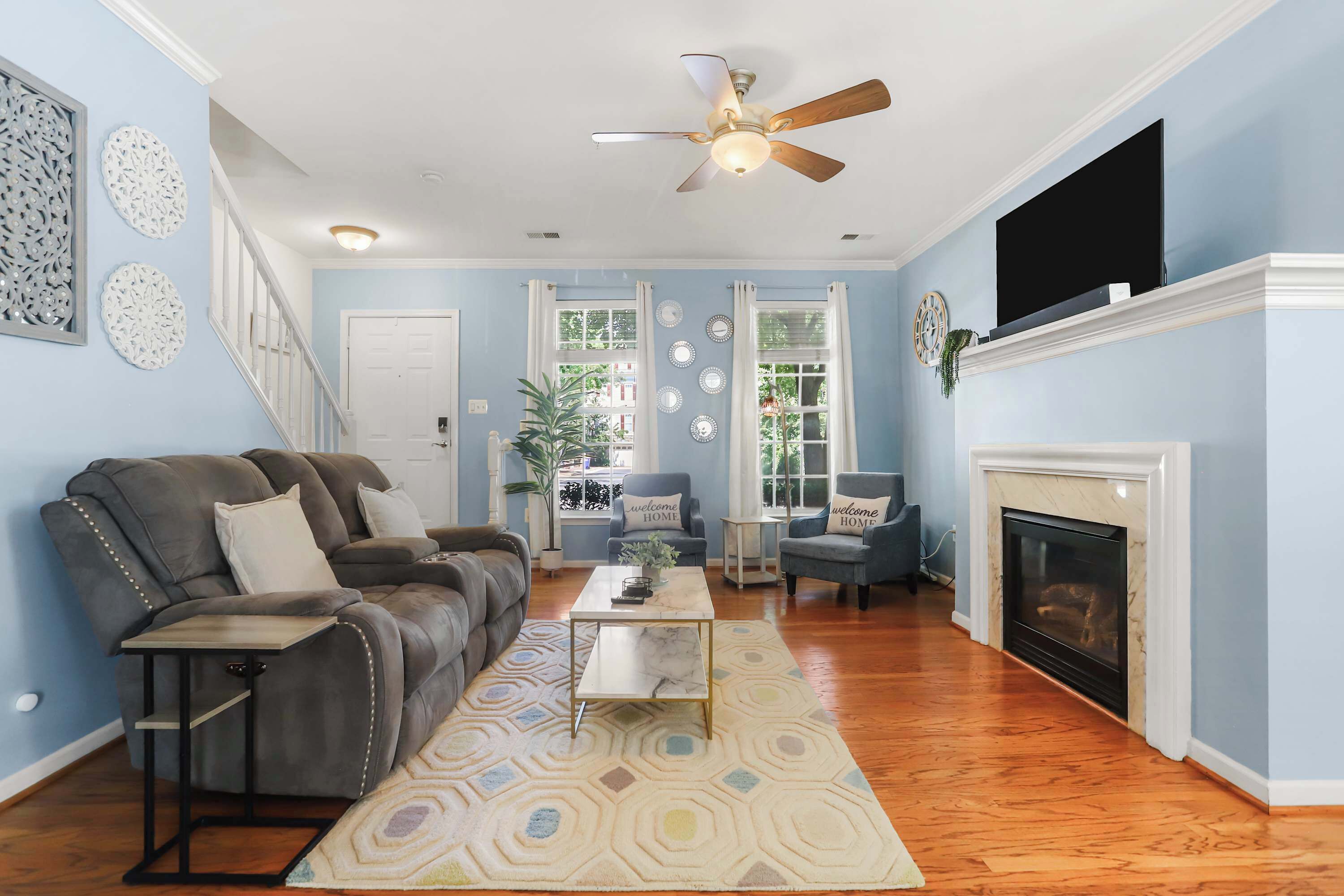 A living room with a fireplace, a ceiling fan, and a television.