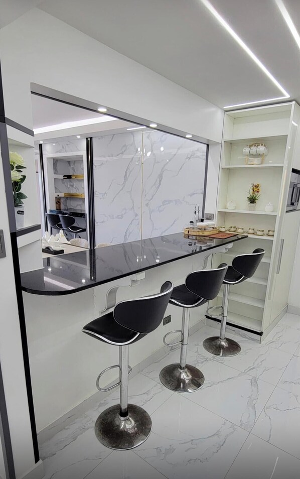 Eine moderne Küche mit Marmor-Spritzschutz, schwarzen Barhocker und einer integrierten Kochinsel mit schwarzer Arbeitsplatte.