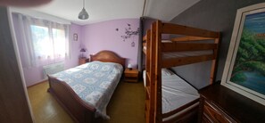 A room with a bunk bed, a bedside table with a lamp, a window with curtains, and a wall-mounted picture. - Welcome to Marco's! A comfortable apartment in the countryside, for 4 people. (Marthod)