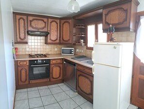 A kitchen with wooden cabinets, a stove, a microwave, and a refrigerator. - Welcome to Marco's! A comfortable apartment in the countryside, for 4 people. (Marthod)