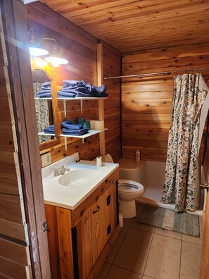 A wooden cabin bathroom with a sink, toilet, and shower. - Hunter's Paradise in Northeast Montana (Culbertson)