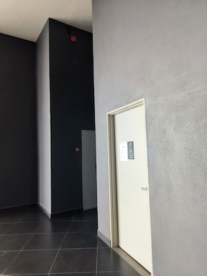 Ein Flur mit einer Tür, auf der 'Damen WC' steht, und einem Rauchmelder an der Wand.