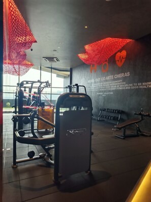 Ein Fitnessraum mit Trainingsgeräten, einer Wand mit motivierenden Texten und großen Fenstern.