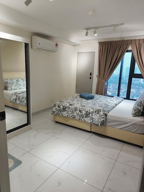 Ein Hotelzimmer mit Bett, einem Fenster mit Vorhängen, einer Tür und einem Spiegel.