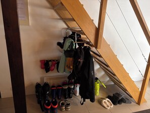 A storage area with various bags, shoes, and a coat rack.