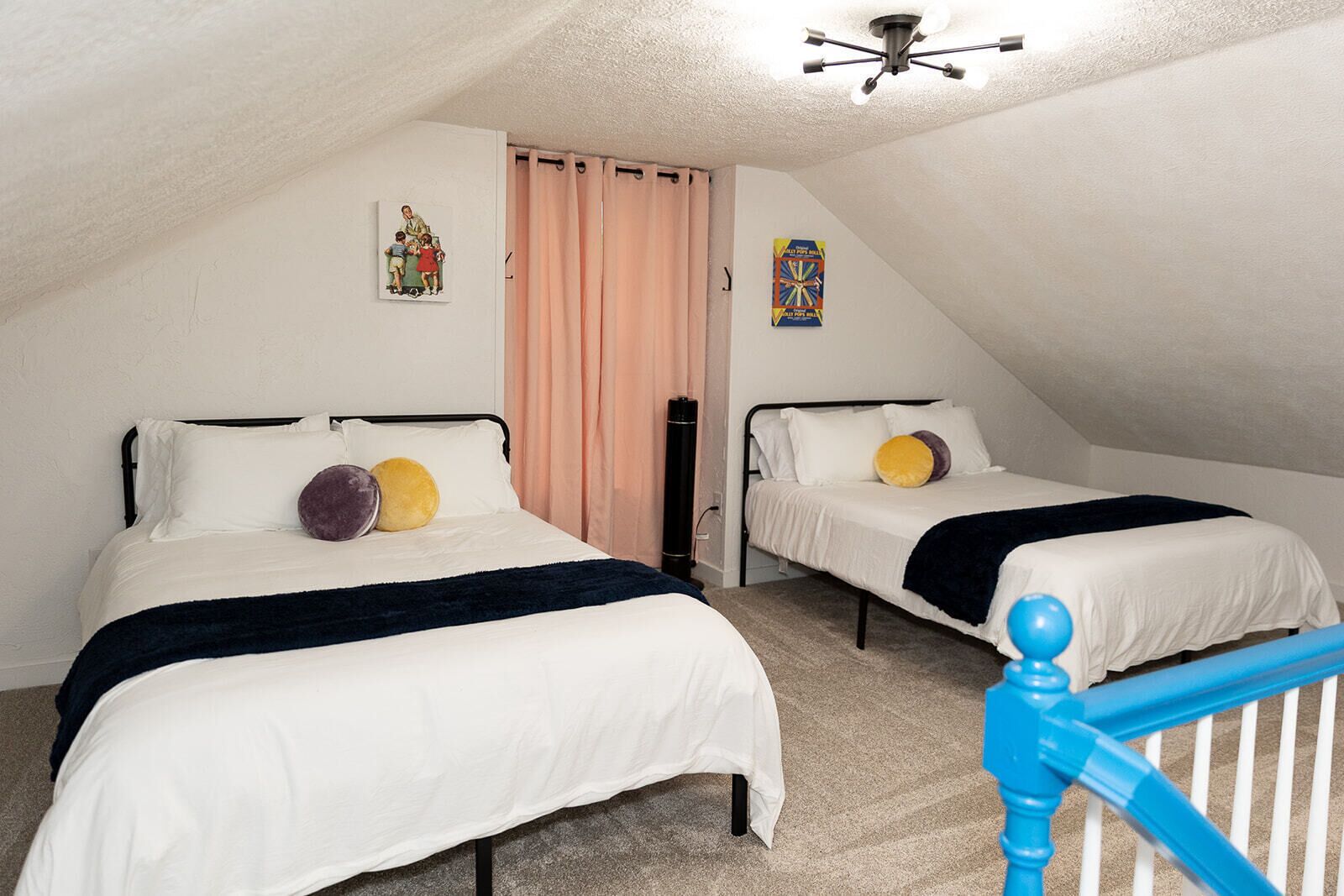 Ein Schlafzimmer mit zwei Betten, einem Deckenventilator und einer Treppe mit einem blauen Geländer.