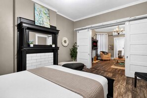 Ein Schlafzimmer mit einem großen Bett, einem Kamin und Blick in den Wohnbereich.