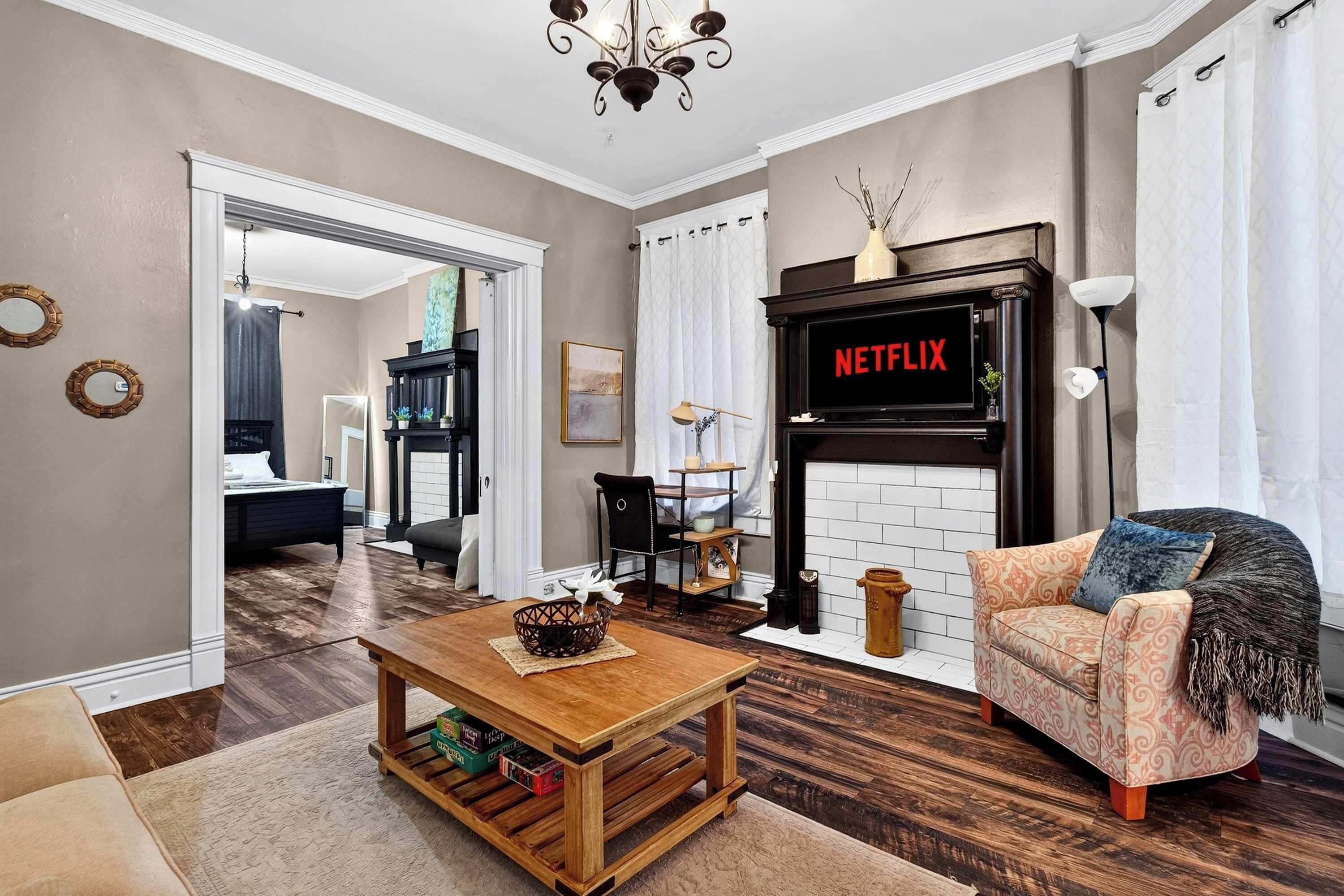 Un salon avec une cheminée, un canapé, une table basse et un téléviseur affichant le logo « NETFLIX ».