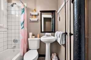 Een badkamer met douche, toilet, wastafel en spiegel.