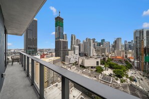 Ein Balkon mit Blick auf eine Stadtlandschaft, darunter hohe Gebäude und ein Baukran.