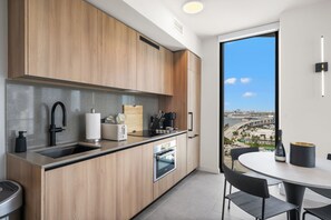 A modern kitchen with wooden cabinets, a built-in oven, and a large window offering a city view. - 501 First Miami | 2BR w/ Pool near Bayfront Park (Miami)