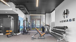 A gym with exercise equipment, a wall-mounted dumbbell rack, and a visible logo. - 501 First Miami | 2BR w/ Pool near Bayfront Park (Miami)