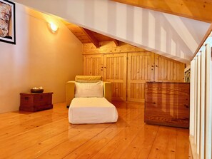 Een knus loft-slaapkamer met een bed, een stoel en houten wanden.