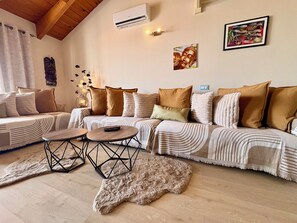Ein gemütliches Wohnzimmer mit einer Couch, zwei runden Tischen, einem Teppich und Wandbildern.