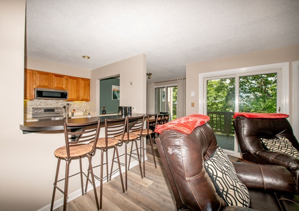 Een moderne keuken met een centraal eiland, eettafels stoelen en een leren bank met een rode plaid.