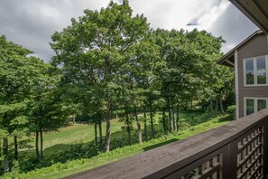 Ein Wohnhaus mit einer Holterrasse mit Blick auf eine begrünte Fläche mit Bäumen.