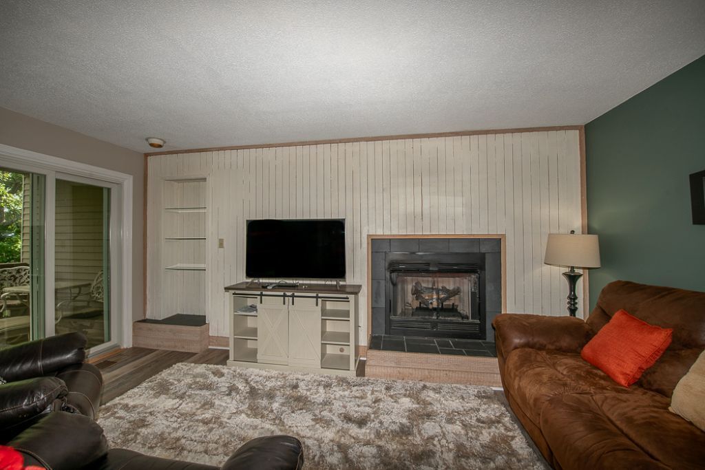 Una sala de estar con televisión, chimenea y un sofá de cuero marrón.