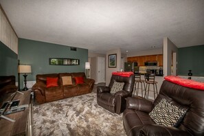 Een woonkamer met een bruine leren bank, een decoratief kussen met een patroon en een vachtkleed.