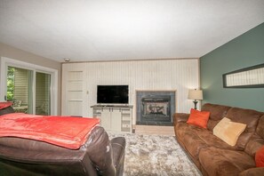 Een woonkamer met een open haard, een televisie en een bank.