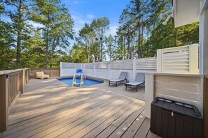 A wooden deck with a pool, lounge chairs, and a white fence. - Outdoor Movie Theater/ Private POOL & Hot Tub/ Fun (Ocean Isle Beach)