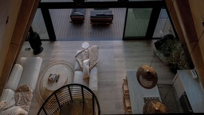 A modern interior with a large triangular skylight, a seating area with cushions, and a staircase leading to an upper level. - Luxury Wellness A-Frame near Zion • Views, Sauna, Cold Plunge & Hot Tub (Glendale)