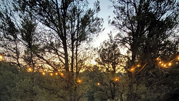 A fire pit surrounded by Adirondack chairs on a gravel surface, with trees and string lights in the background. - Luxury Wellness A-Frame near Zion • Views, Sauna, Cold Plunge & Hot Tub (Glendale)