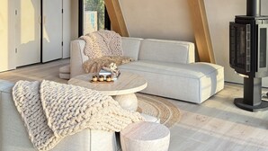 A modern living room with a sectional sofa, a round coffee table, and a fireplace. - Luxury Wellness A-Frame near Zion • Views, Sauna, Cold Plunge & Hot Tub (Glendale)