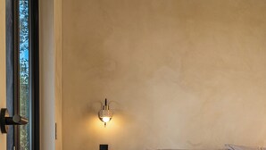 A bedroom with a bed, a nightstand, a wall-mounted light, and a window. - Luxury Wellness A-Frame near Zion • Views, Sauna, Cold Plunge & Hot Tub (Glendale)