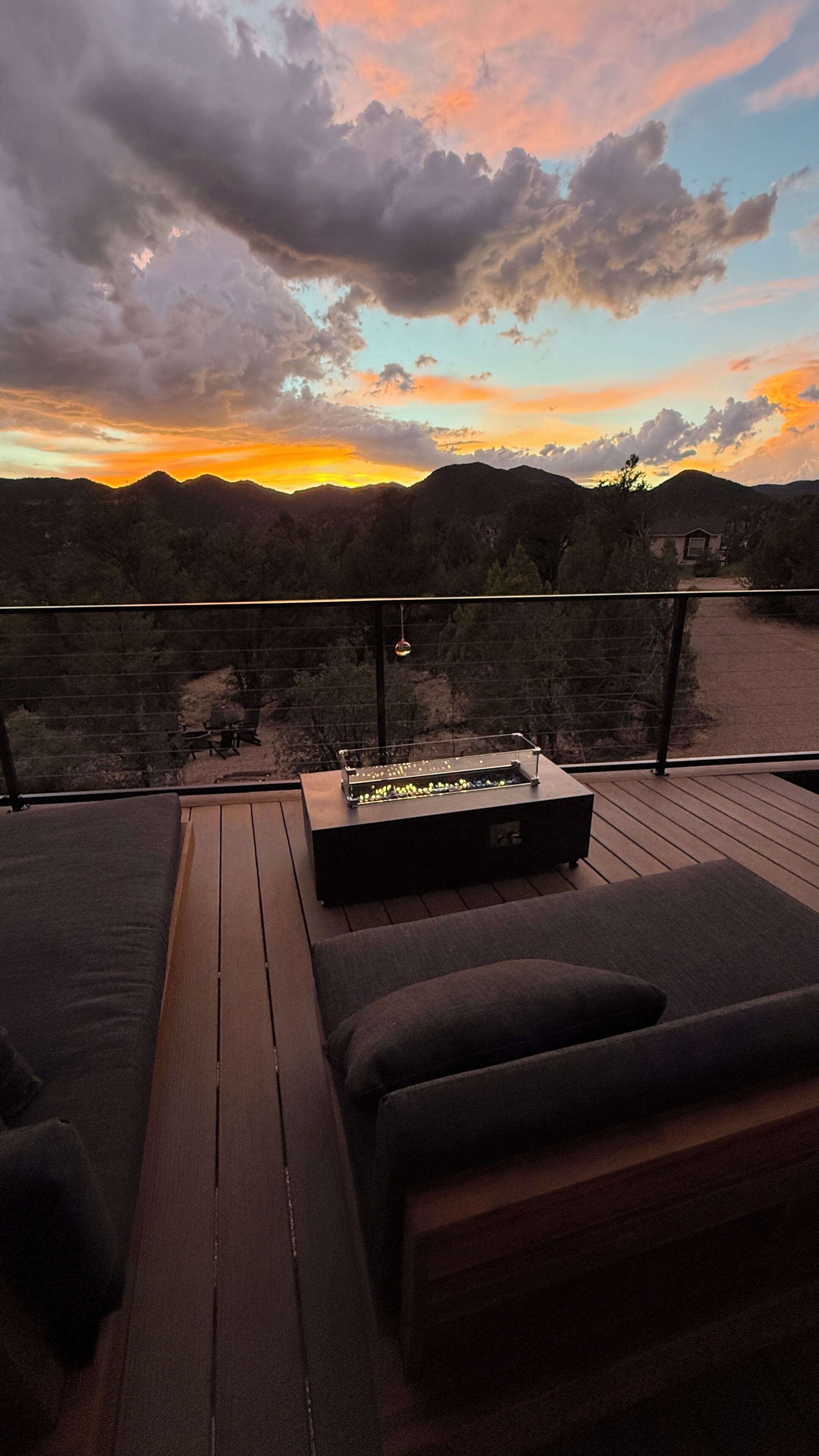 Eine Terrasse mit Sitzgelegenheit und Tisch, mit Blick auf eine gebirgige Landschaft.