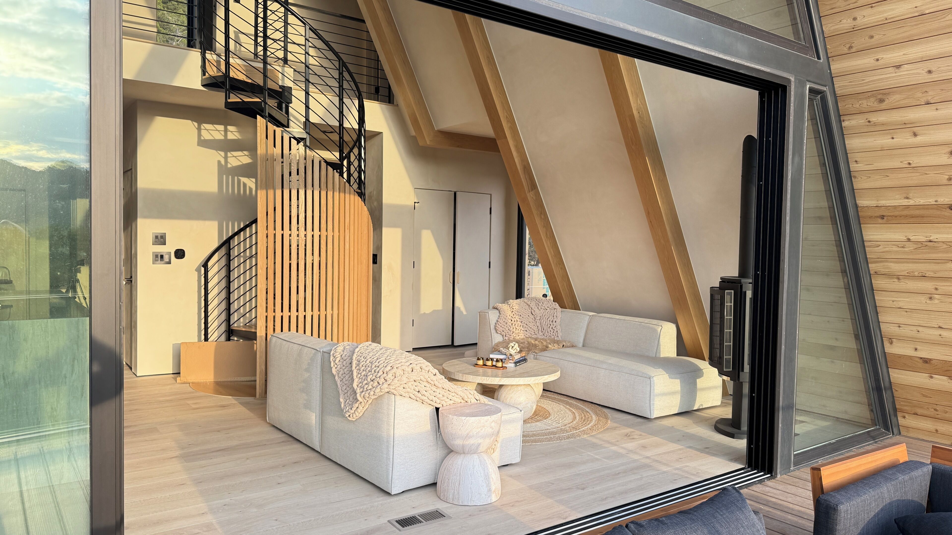 Een modern interieur met een gebogen trap, een zithoek, een salontafel en een grote glazen deur.