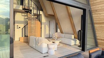 Een modern interieur met een gebogen trap, een zithoek, een salontafel en een grote glazen deur.