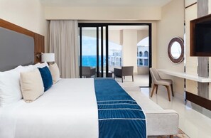 Una habitación de hotel con una cama grande, un escritorio, una silla, un televisor y vista al mar.