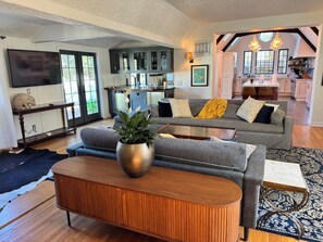 Ein modernes Wohnzimmer mit einem grauen Sofa, einem Holztisch und einer großen Pflanze.