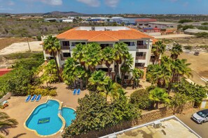 Ein mehrstöckiges Hotel mit Pool, Palmen und Blick auf die umliegende Landschaft.