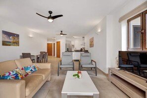 A modern living room with a sofa, chairs, a coffee table, and a TV. There is a kitchen in the background with a dining area. - Bon Bida Buriku with shared pool, Hato (Kralendijk)