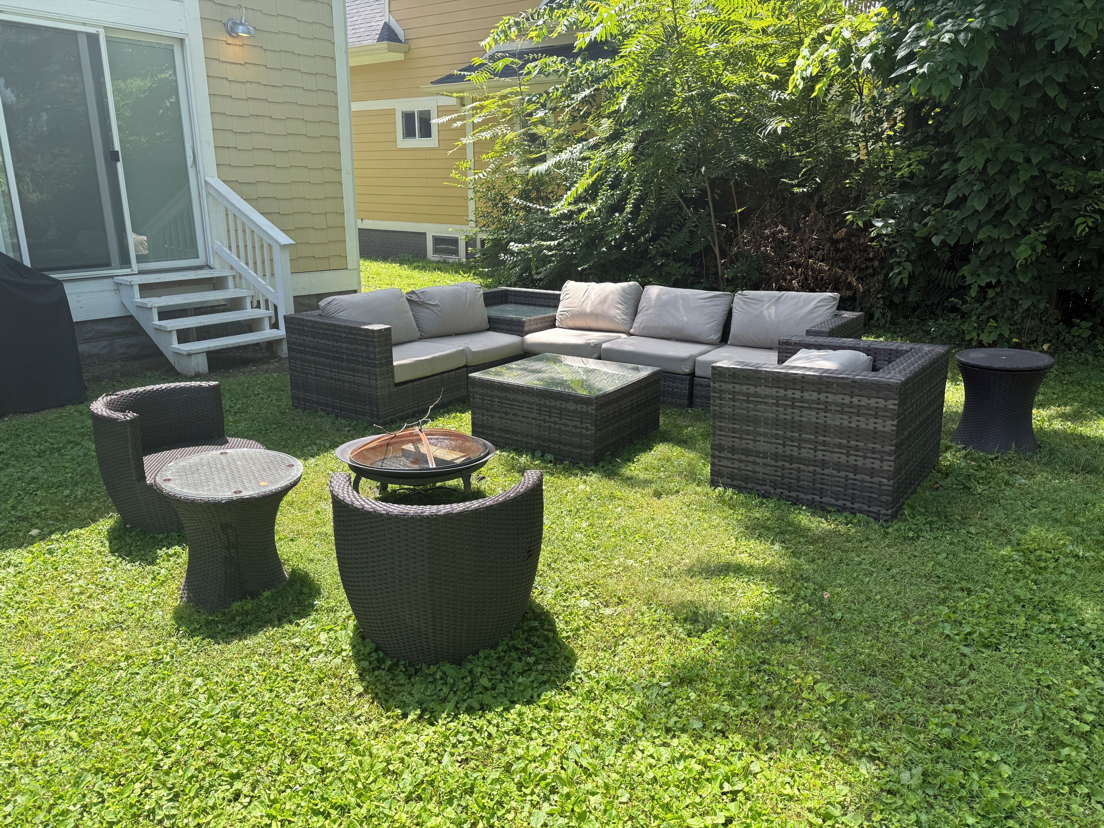An outdoor seating area with a sectional sofa, two round tables, and a fire pit.