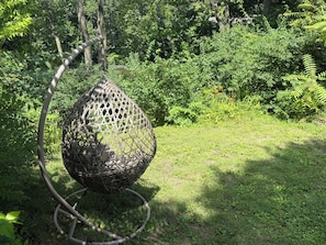 A spherical, woven outdoor seating structure in a lush garden setting.