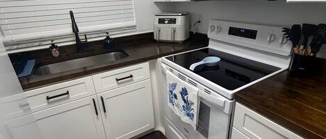 Una cocina compacta con armarios blancos, un microondas, un horno y un lavamanos.