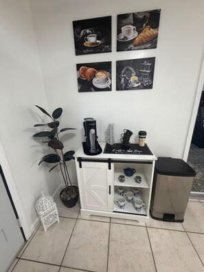 A small kitchenette with a coffee machine, a plant, and a trash bin. - Rainbow Springs Retreat — Your Perfect Dunnellon Getaway (Dunnellon)